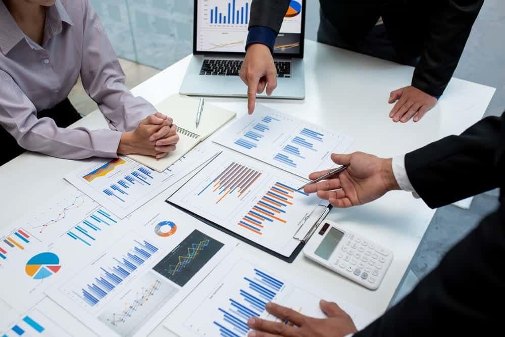 Financial analysis meeting with charts and graphs on a desk.